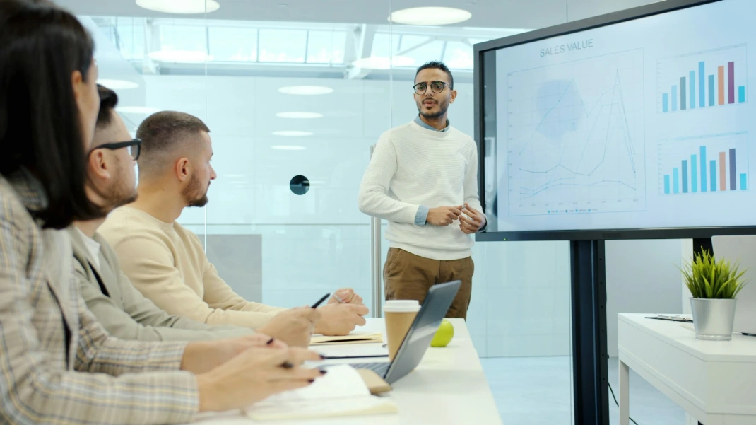 Man presenting charts to colleagues in a meeting.